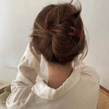 U-shaped brown faux tortoise shell hair pin styling on model in a cozy indoor setting
