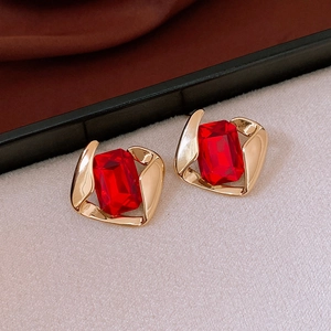 Detail of gold spiral frame earrings with red rectangular zircon stones in premium setting