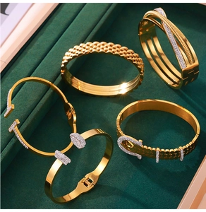 Close-up of four gold titanium bracelets featuring diamond-set T-shapes and woven textures