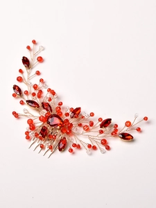 Detailed close-up of a handmade gold wire hair comb with red crystals and beads