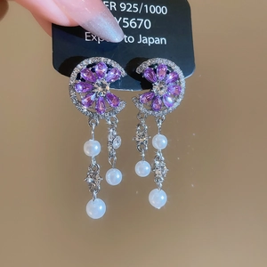 Macro detail of silver flower earrings with purple zircons, pearls and starburst effect