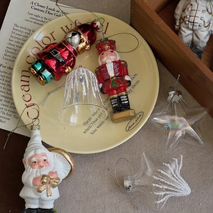 Flat lay of resin Christmas ornaments including nutcracker, bear and bell on a cream tray