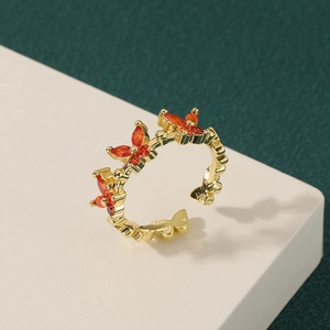 Elegant gold butterfly ring with orange cubic zirconia on a minimalist textured surface
