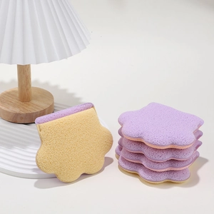 Cat paw shaped face cleansing sponges in purple and yellow on a minimalist white surface