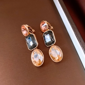 Detail of vintage gold earrings with pink, black and champagne crystals on brown background