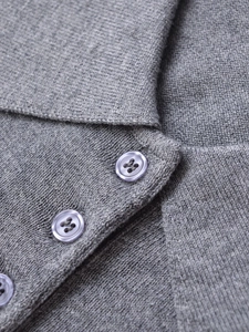 Macro detail of grey knit polo sweater neckline with translucent buttons and fine texture