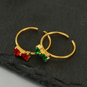Detail showing two gold bow rings with red and green heart gems on black stone