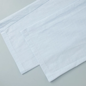 Detail view of light blue cotton-linen fabric texture on wide-leg trousers hemline