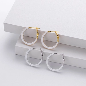 Close-up of gold and silver hoop earrings with white inlay on minimalist white props