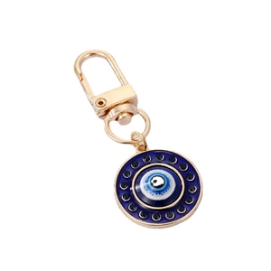 Porte-clés œil protecteur doré avec strass bleus et pendentif émaillé sur fond blanc