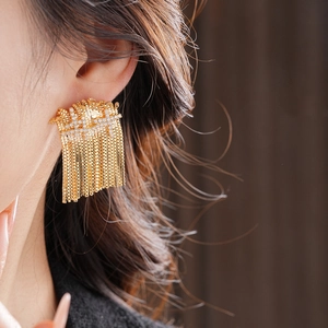 Détail macro de boucles d'oreilles pampilles dorées avec oxydes de zirconium sur un modèle
