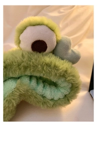 Primo piano della fascia per capelli a rana in peluche verde con dettagli morbidi