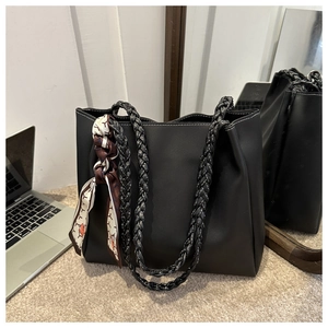 Gros plan du sac cabas en cuir noir mat avec coutures blanches et anses tressées