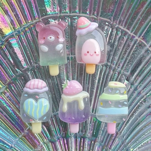 Gros plan de charms popsicle en résine colorée avec détails d'ours et de coeurs