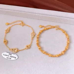 Détail d'un bracelet plaqué or 24k avec breloques calebasse, pièce et zircons sertis