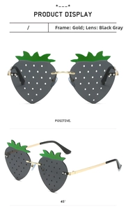Detail of strawberry shaped sunglasses with grey lenses and gold metal temples