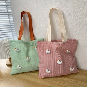 Detail of striped canvas tote bags featuring cute 3D duck dolls and soft handle straps