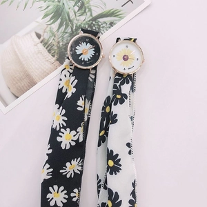 Detail view of two quartz watches featuring daisy patterns and fabric ribbon straps