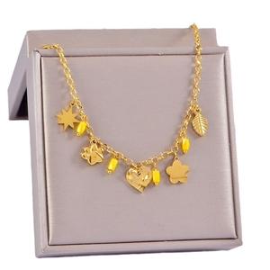 Bracelet doré avec pendentifs étoile, cœur et fleur sur une boîte à bijoux élégante