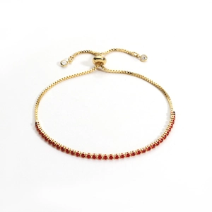Detail of golden bolo bracelet with red round cubic zirconia and adjustable chain slide