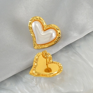 Detail of heart-shaped pearl earrings featuring golden hammered edges and butterfly backings