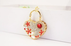 Detail of heart keychain with red flowers, crystals, and large red gemstone on gold base