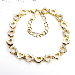 Detail of heart-shaped gold bracelet featuring sparkling zircon accents and adjustable clasp
