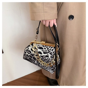 Detail of leopard print shell bag with golden metal frame and chain strap on trench coat