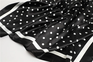 Detail of soft black square scarf featuring white polka dots and a silky satin texture
