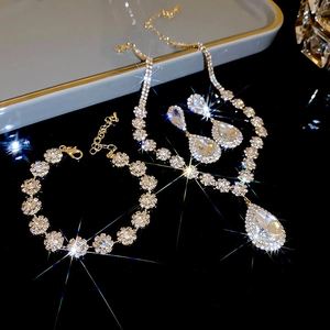 Close-up of sparkling teardrop pendant necklace and crystal earring set on black background