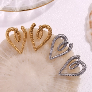 Macro detail of twisted rope texture and heart shape design on gold and silver earrings