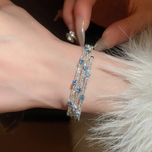 Macro shot of three-layered silver bracelet with sparkling zircons and blue gemstones