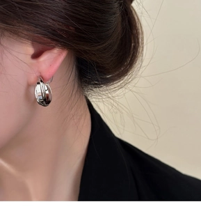 Gros plan d'élégantes boucles d'oreilles créoles géométriques argentées multicouches