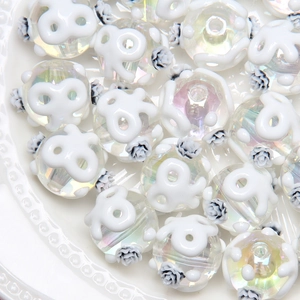 Detail of iridescent beads with white floral relief and grey rose pattern on ceramic plate