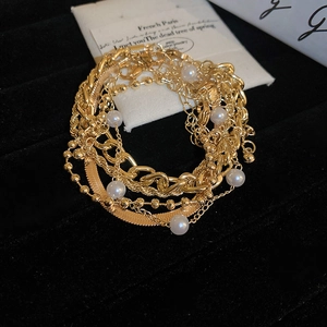 Detail of layered gold chain bracelet set with imitation pearls on black velvet