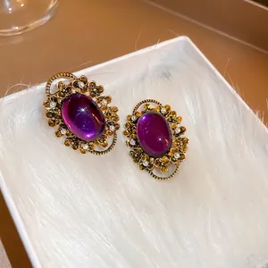 French vintage purple oval pearl ear clip with gold floral engraving on plush background