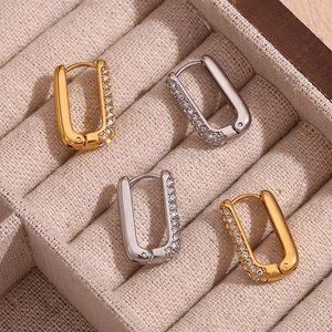 Detailed view of gold and silver U-shaped hoop earrings with zircon stones in a jewelry box