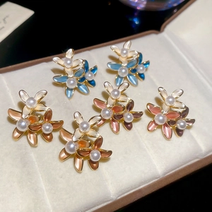 Detailed macro of 18K gold-plated floral pearl earrings with enamel petals in three colors