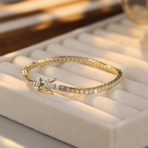 Macro shot of gold tennis bracelet with square clear cubic zirconia and secure side clasp