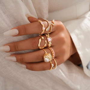 Detail of model wearing gold irregular geometric rings with pearls and zircon stones