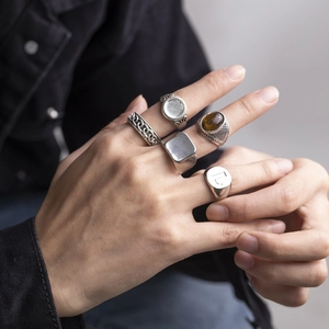 Detail of five vintage silver-style rings with gemstones and engravings on a model's hand