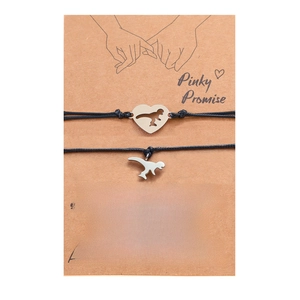 Close-up of dinosaur charms on woven bracelets with Pinky Promise display card
