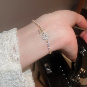 Detailed close-up of a gold star and heart charm bracelet with cubic zirconia inlay