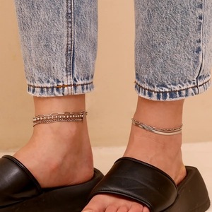 Three-layer silver layered anklet featuring bead and snake chains on model ankle
