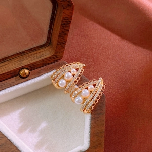 Macro detail of vintage gold pearl earrings with shimmering cubic zirconia and lace carving