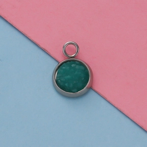 Close-up of 12mm silver stainless steel pendant with green faux gemstone on split background