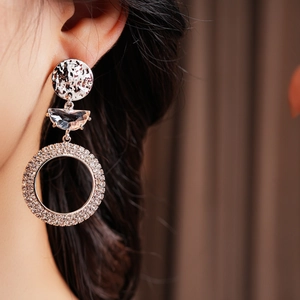 Macro shot of silver crescent earrings with sparkling pavé crystals on a model