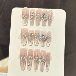 Detail of luxury press-on nails with pink gradient, silver glitter, and large crystal rhinestones