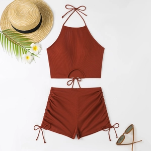 Flat lay of red ribbed bikini set with lace-up detail and summer vacation props