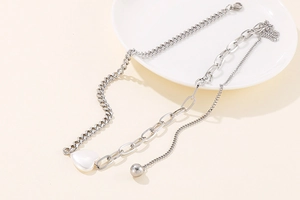 Detail of silver dual-layer necklace with heart shell pendant on a white ceramic plate